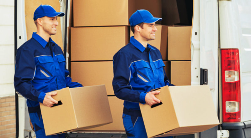 Happy family standing with moving boxes in their new home, successfully moved by the best movers and packers in Dubai from dxbmovershub.com.
