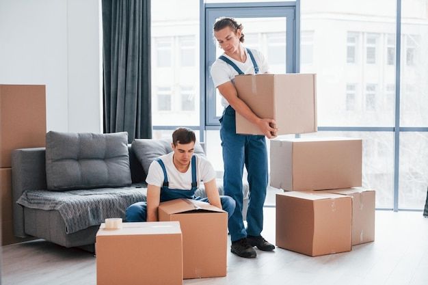 Two best movers and packers in Dubai professionally handling and preparing items for packing inside a modern living room, demonstrating careful and efficient service.