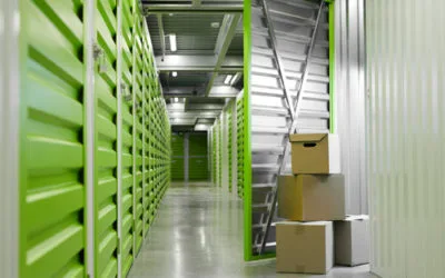 Indoor view of a clean, secure, climate-controlled storage facility hallway with green metal units. Dependable storage services in Fujairah by dxbmovershub.com.